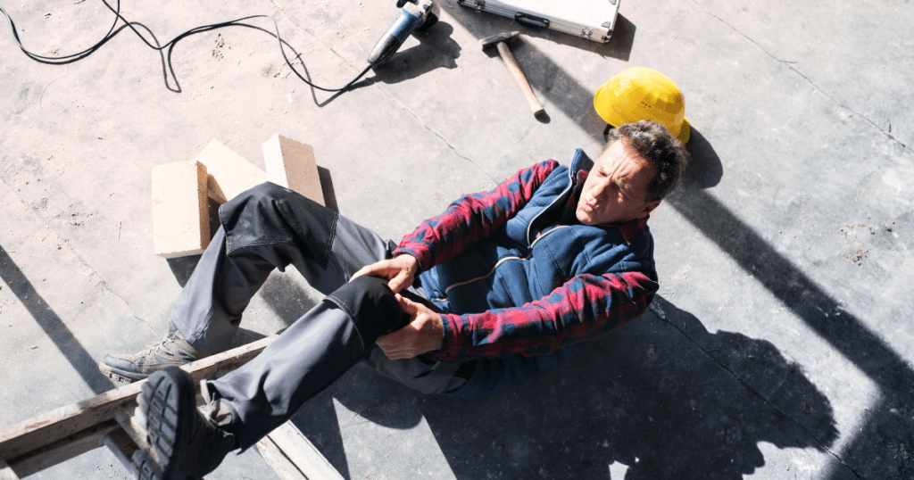 injured construction worker gripping his left knee